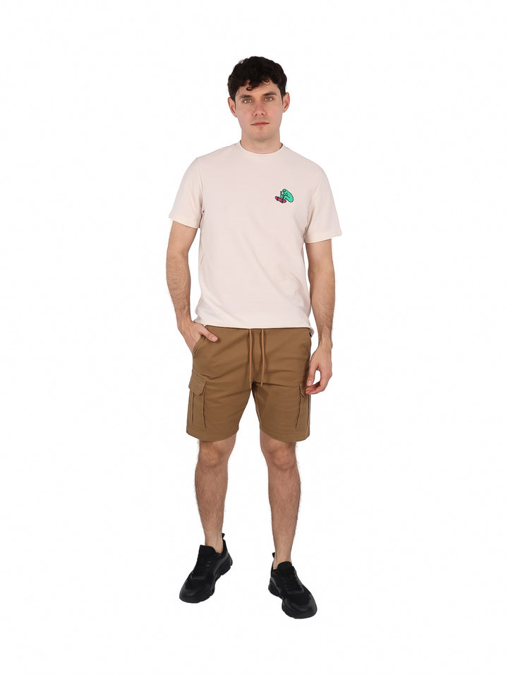 Hombre vistiendo playera de manga corta color hueso con un pequeño estampado en el pecho.
