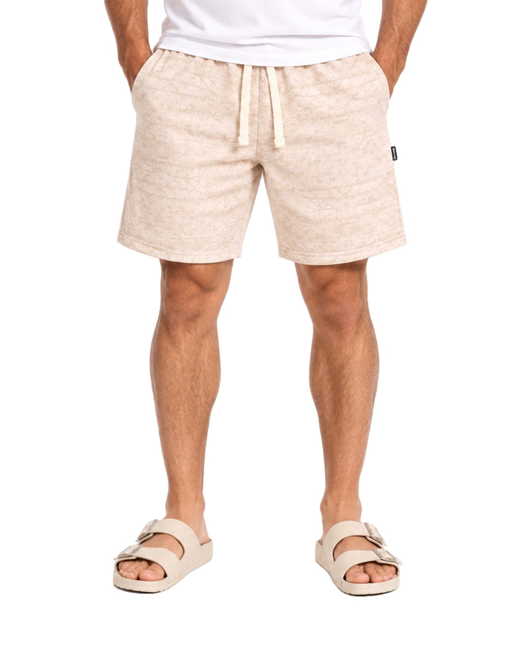 Hombre vistiendo short Action Gear estampado en color hueso con cordón ajustable y sandalias claras.