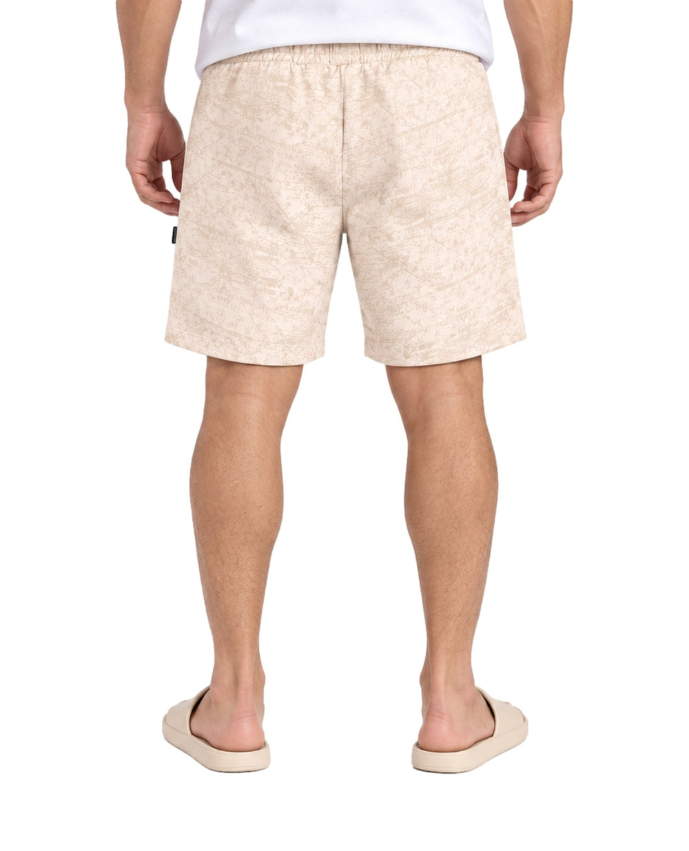 Hombre vistiendo short Action Gear estampado en color hueso con cordón ajustable y sandalias claras.