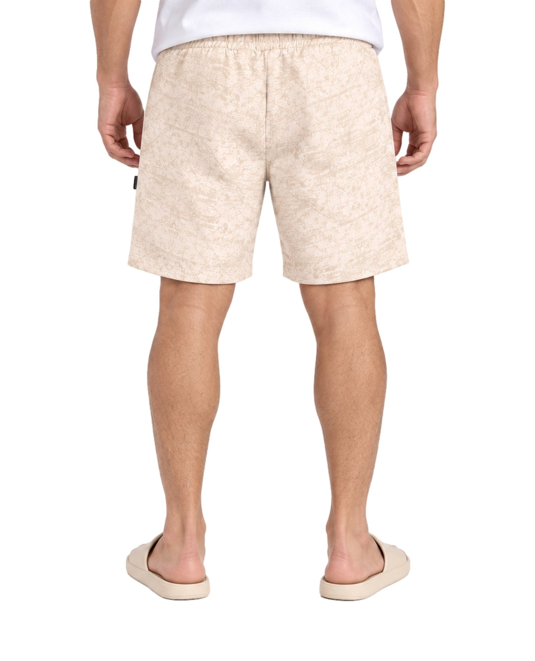 Hombre vistiendo short Action Gear estampado en color hueso con cordón ajustable y sandalias claras.