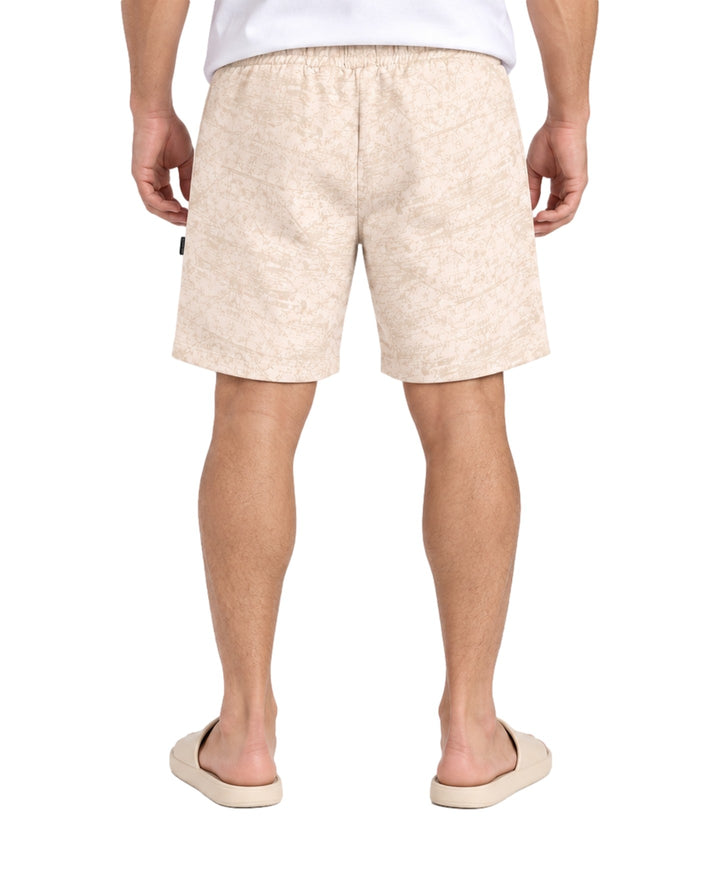 Hombre vistiendo short Action Gear estampado en color hueso con cordón ajustable y sandalias claras.