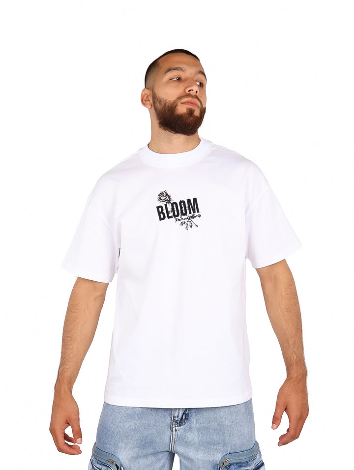 Hombre vistiendo una playera blanca de manga corta con estampado negro en el pecho que dice BLOOM.