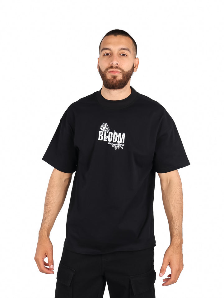 Hombre vistiendo playera color negro de manga corta con estampado blanco en el pecho.