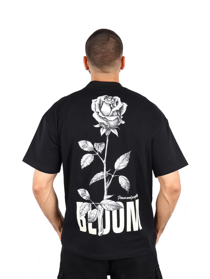 Hombre vistiendo playera color negro de manga corta con estampado blanco en el pecho.