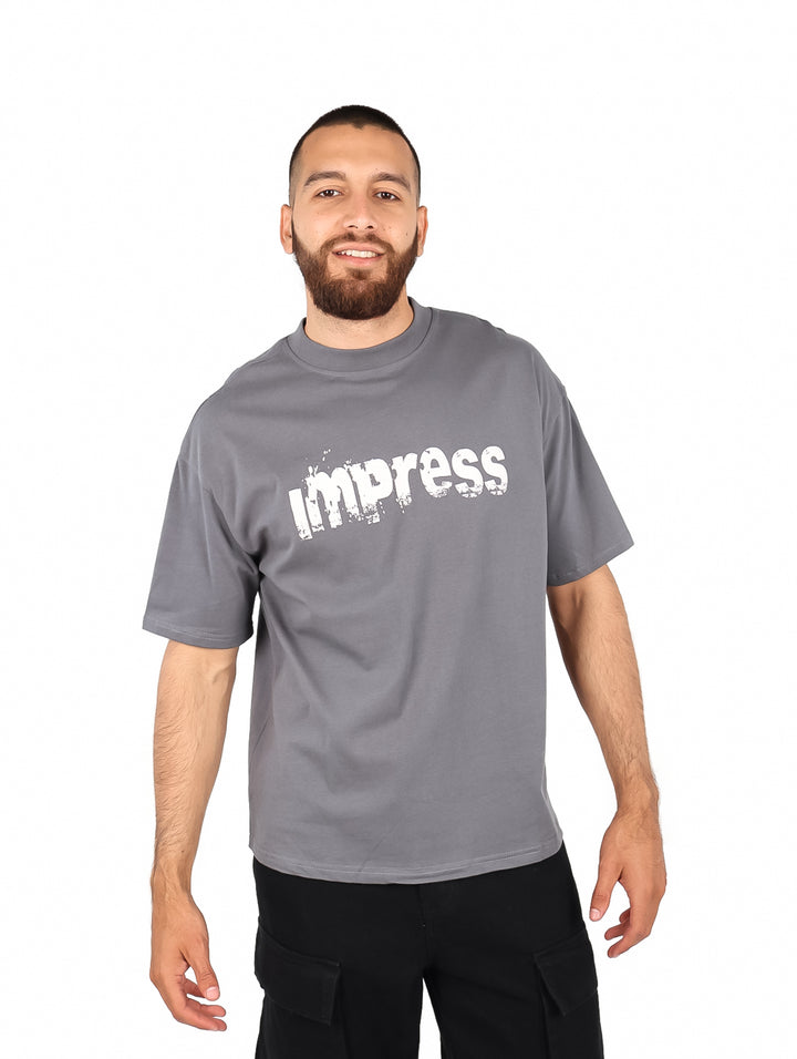 Hombre vistiendo una playera gris de manga corta con el texto &