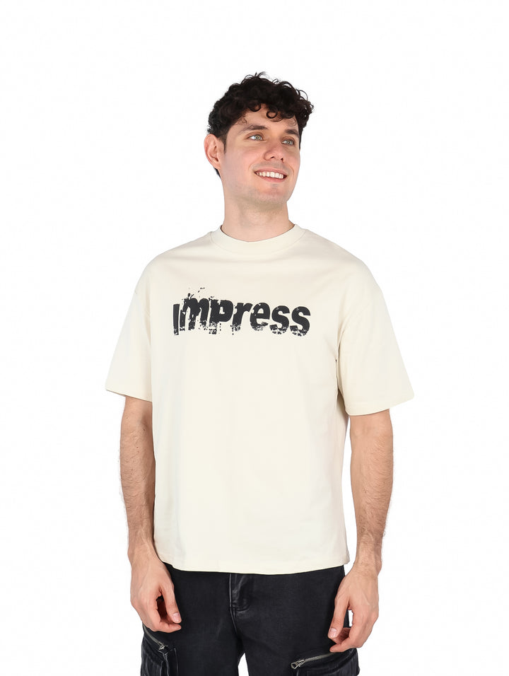 Hombre vistiendo una playera color beige con estampado negro en el pecho.