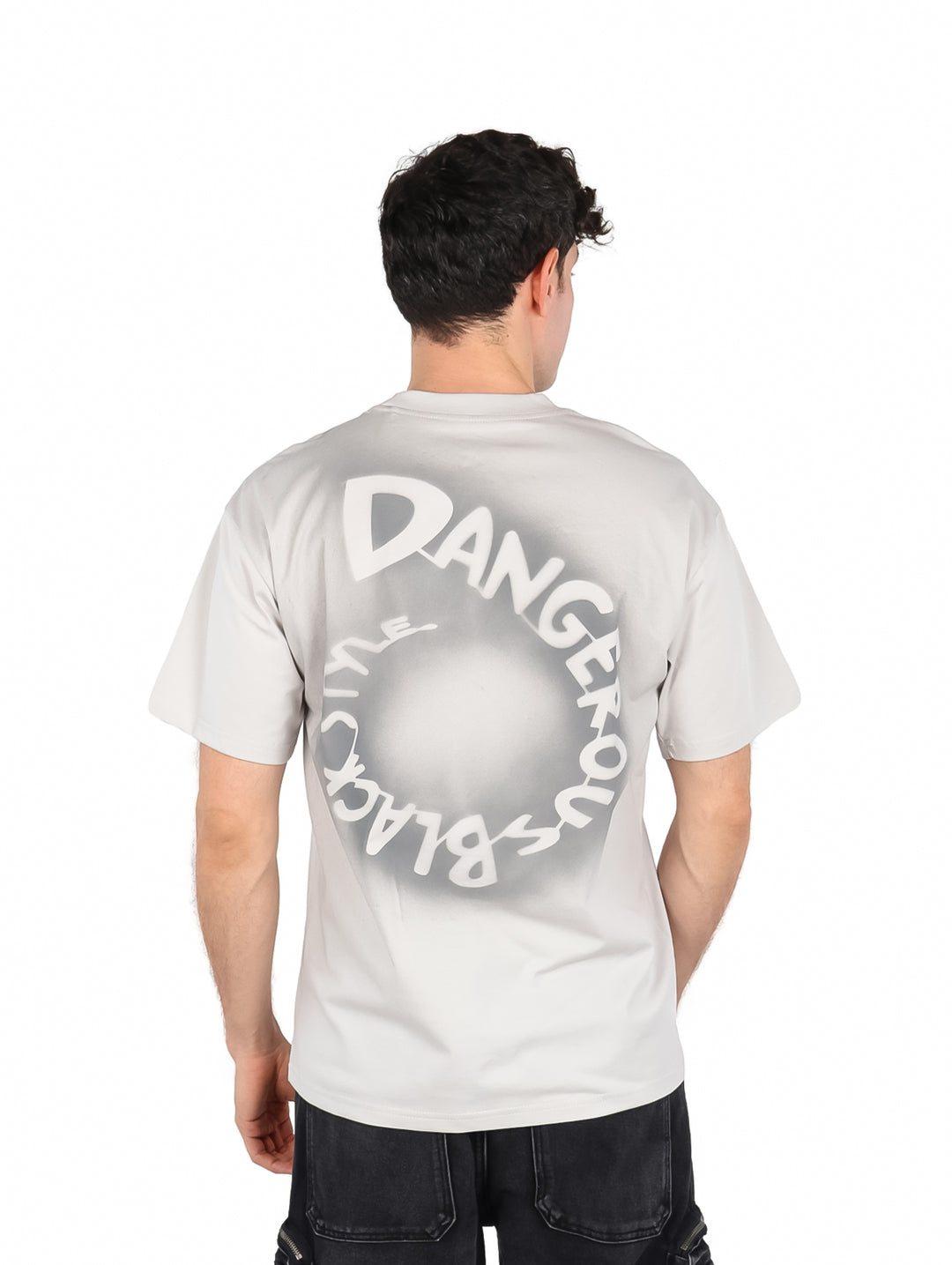 Hombre vistiendo una playera de manga corta color gris con cuello redondo y un pequeño detalle rectangular en el pecho.