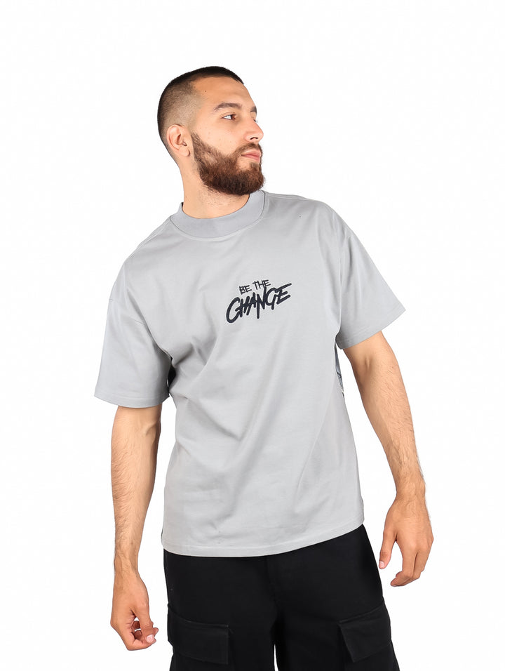 Hombre vistiendo playera color gris de manga corta con estampado frontal que dice &