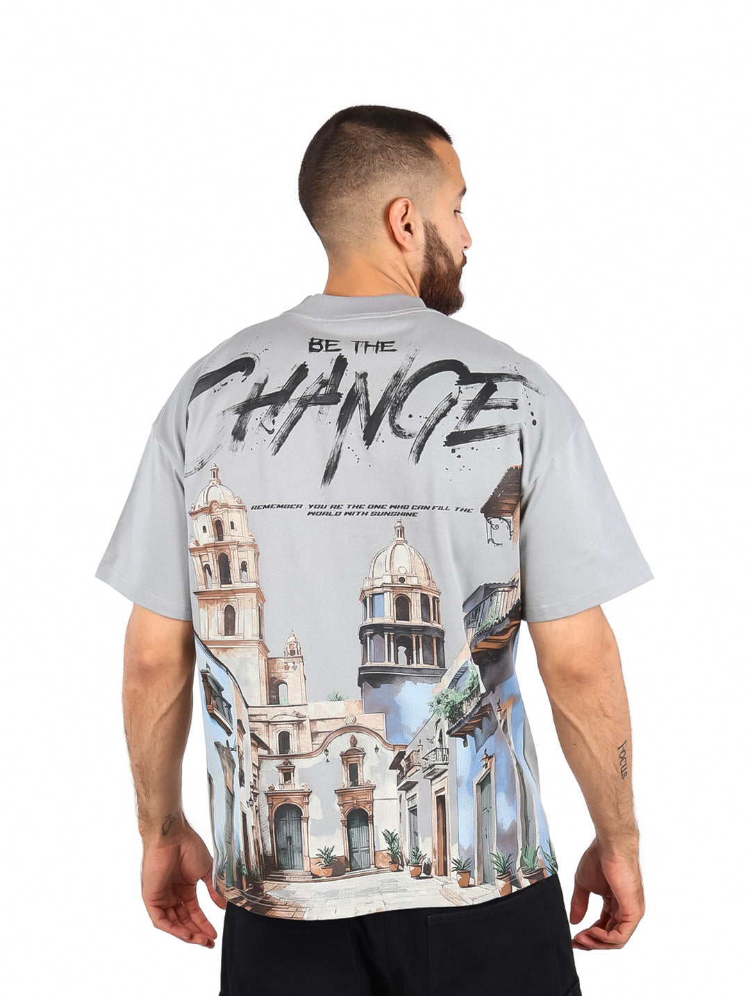 Hombre vistiendo playera color gris de manga corta con estampado frontal que dice &