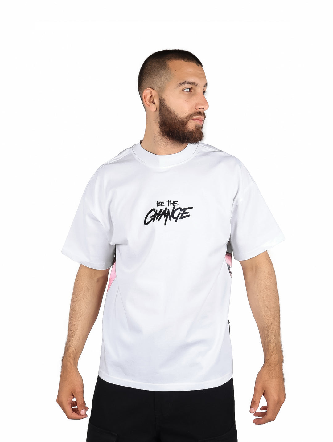 Hombre usando playera blanca de manga corta con detalles laterales en rosa y texto negro al frente.