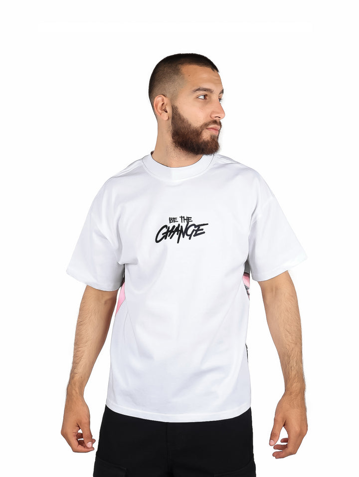 Hombre usando playera blanca de manga corta con detalles laterales en rosa y texto negro al frente.
