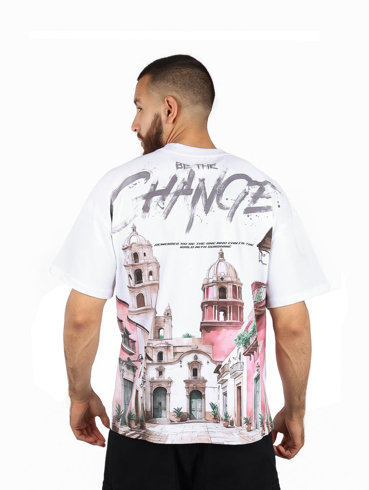 Hombre usando playera blanca de manga corta con detalles laterales en rosa y texto negro al frente.