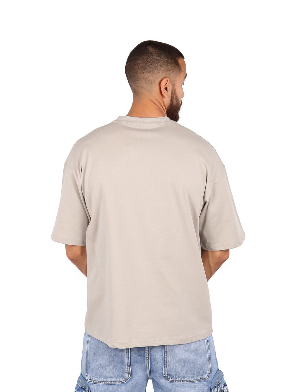 Hombre vistiendo una playera de manga corta color gris claro de corte amplio y cuello redondo.