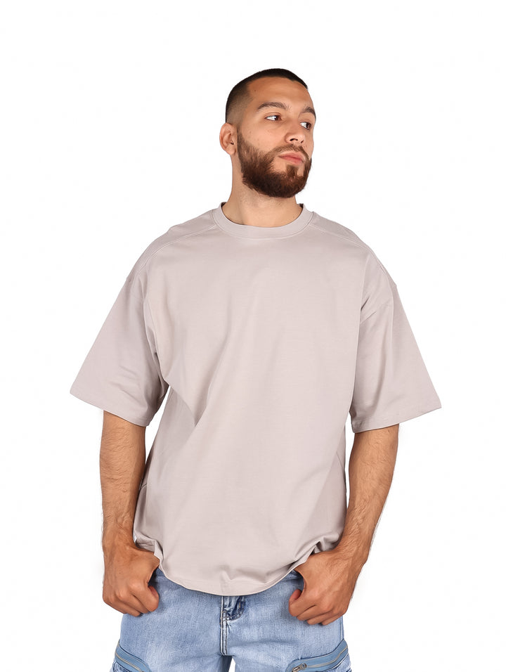Hombre vistiendo una playera gris de manga corta y corte amplio.