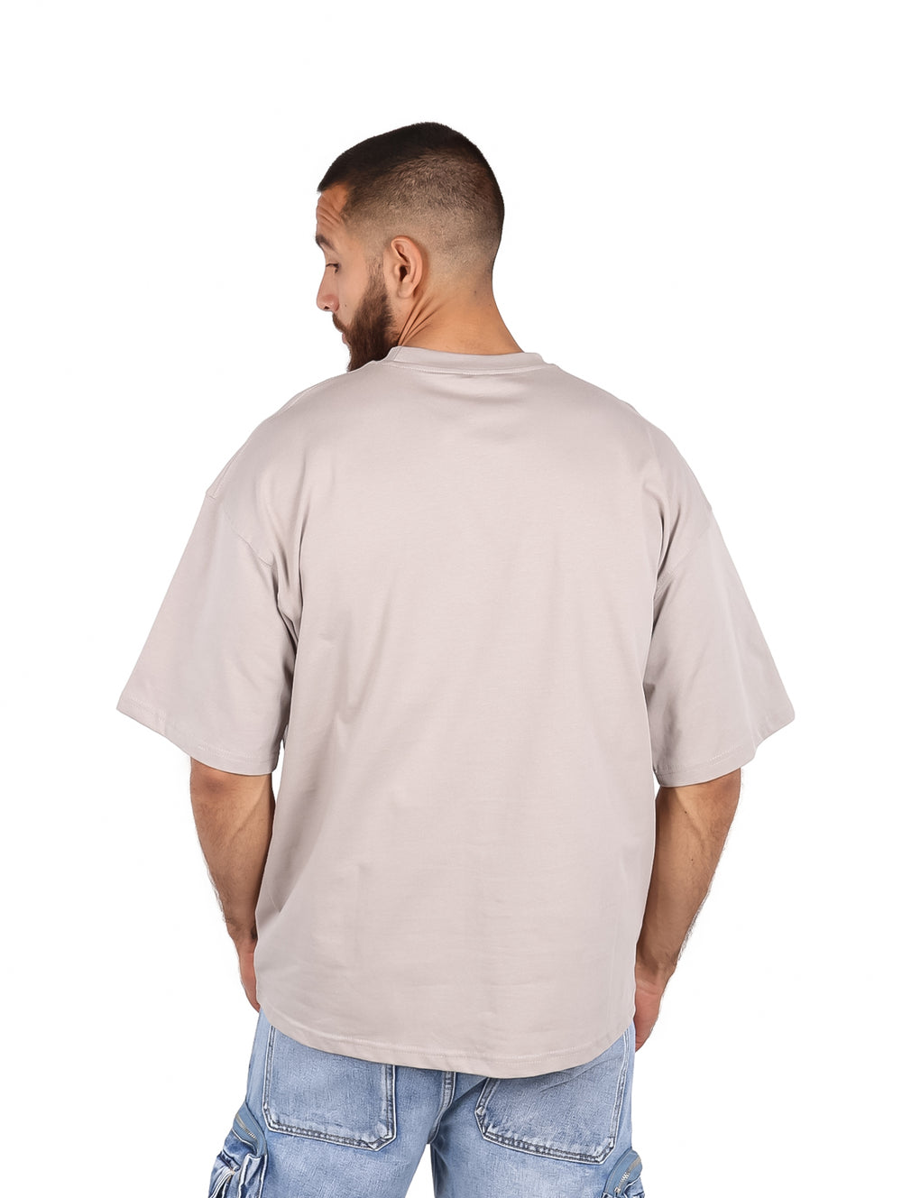 Hombre vistiendo una playera gris de manga corta y corte amplio.