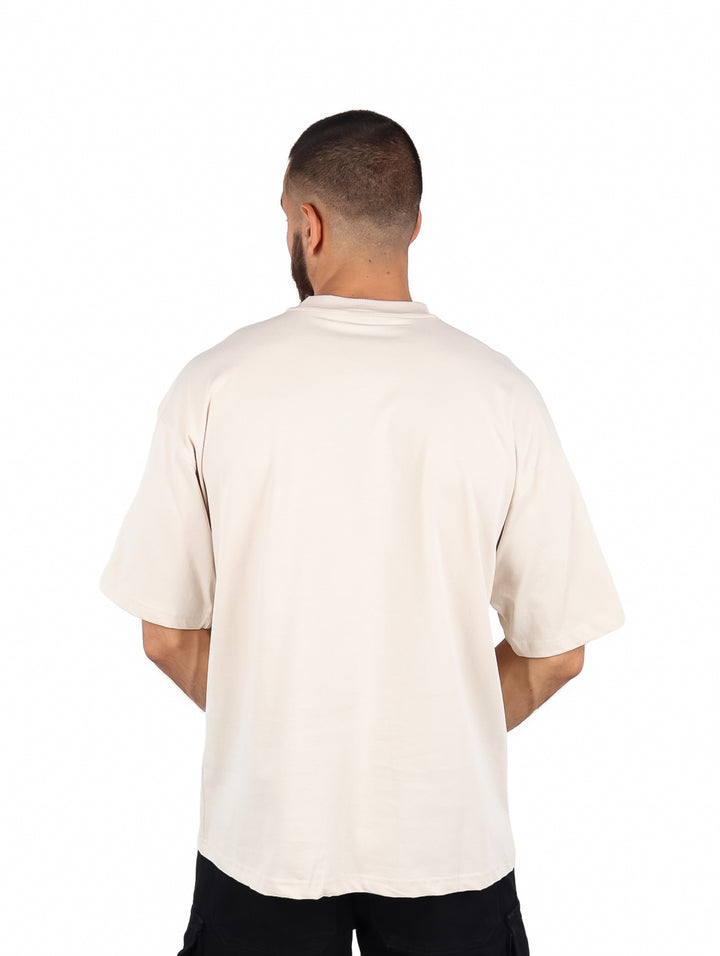 Hombre vistiendo una playera color beige de manga corta y cuello redondo.