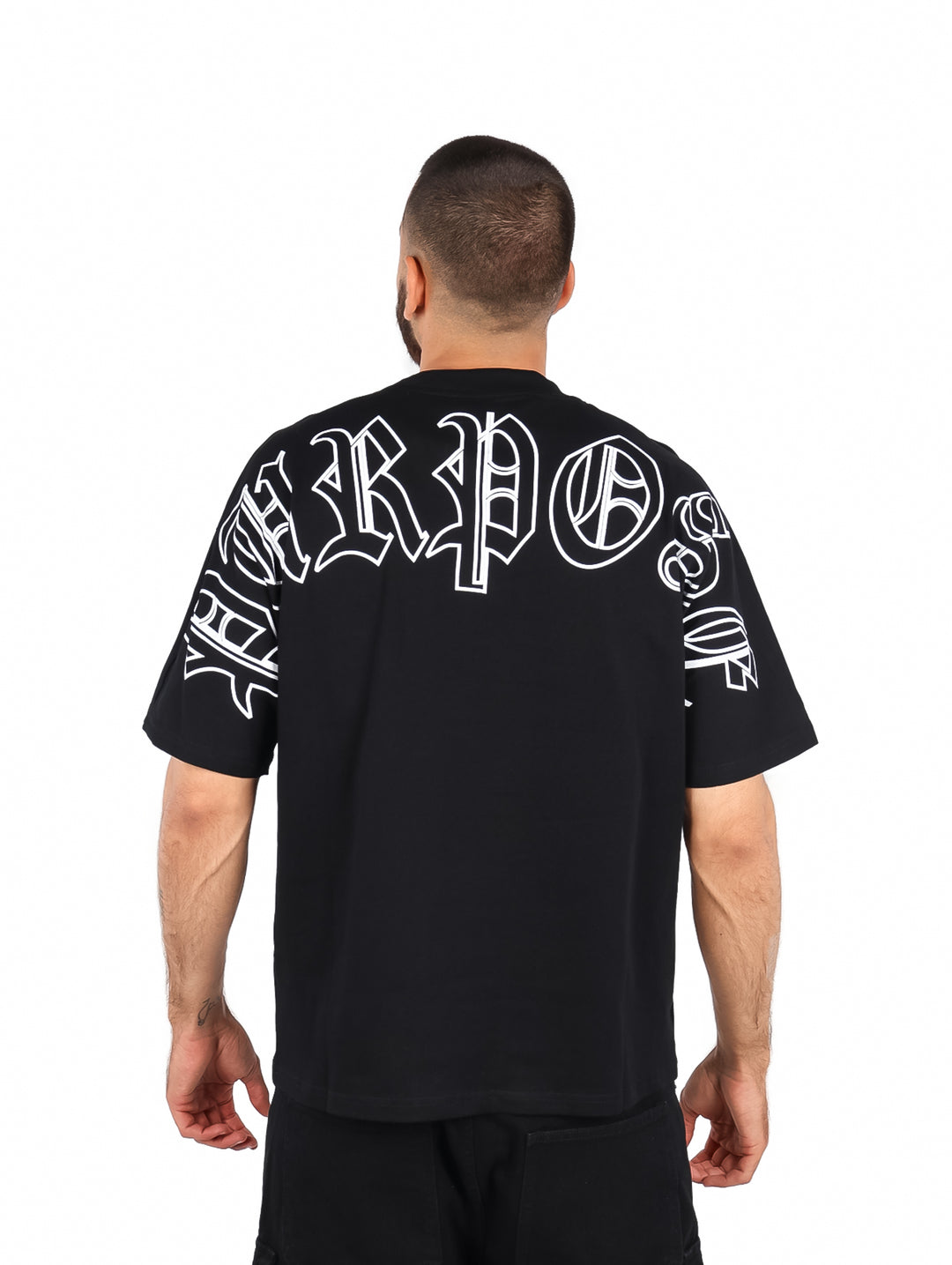 Hombre vistiendo playera negra de manga corta con la palabra PURPOSE en letras blancas en el pecho.