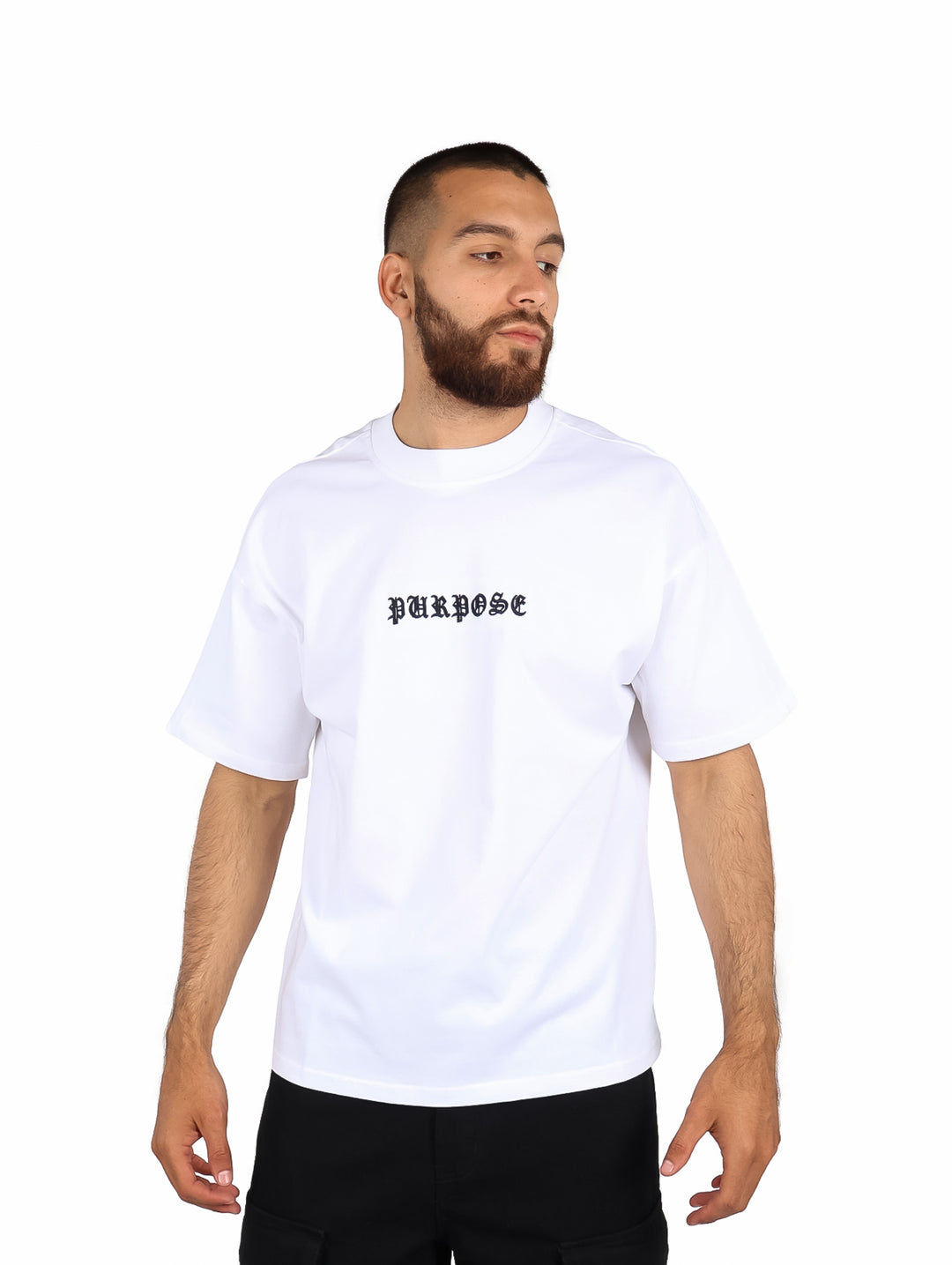 Hombre vistiendo playera blanca de manga corta con la palabra PURPOSE en el pecho.