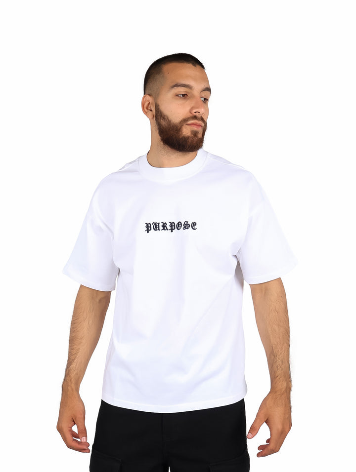 Hombre vistiendo playera blanca de manga corta con la palabra PURPOSE en el pecho.