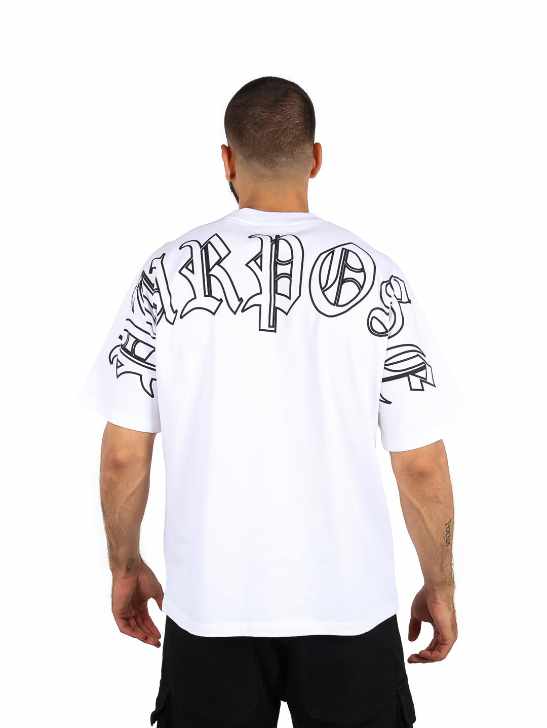 Hombre vistiendo playera blanca de manga corta con la palabra PURPOSE en el pecho.