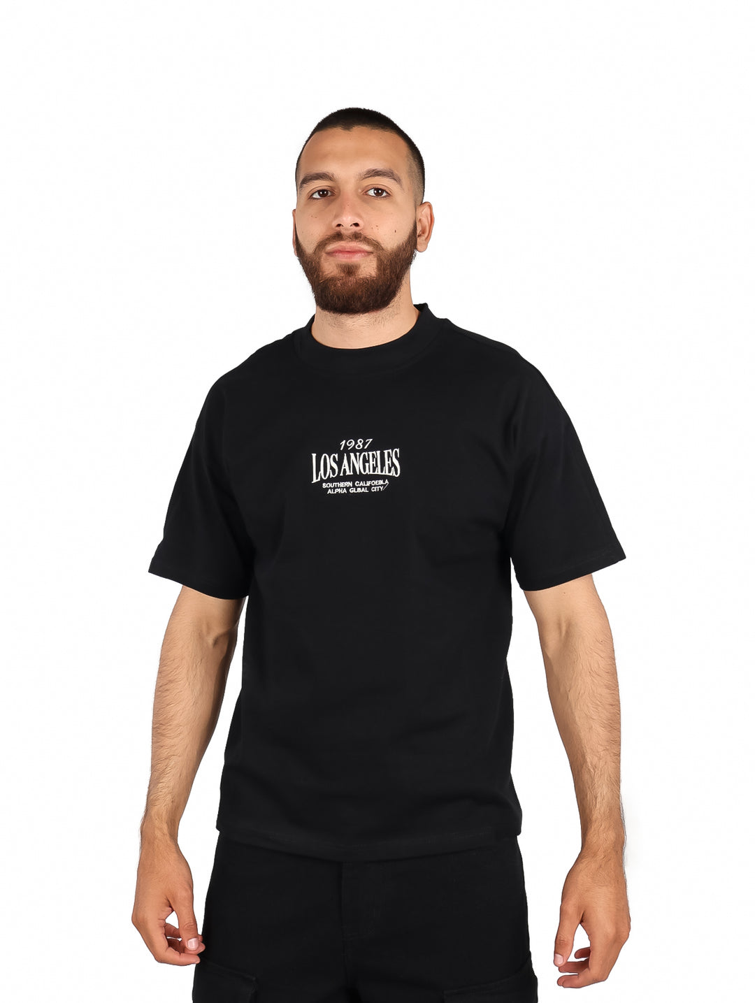 Hombre vistiendo playera negra de manga corta con estampado blanco de Los Angeles en el pecho.