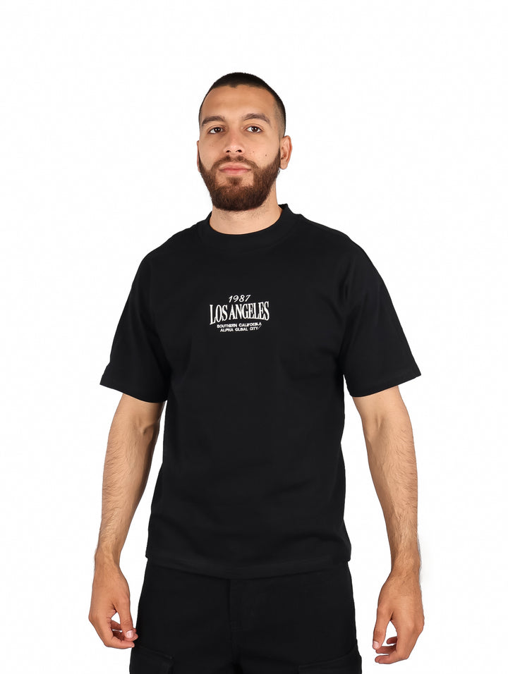 Hombre vistiendo playera negra de manga corta con estampado blanco de Los Angeles en el pecho.