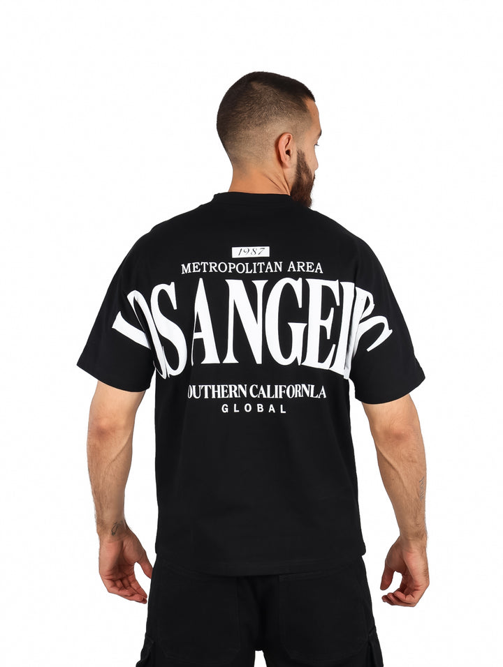 Hombre vistiendo playera negra de manga corta con estampado blanco de Los Angeles en el pecho.