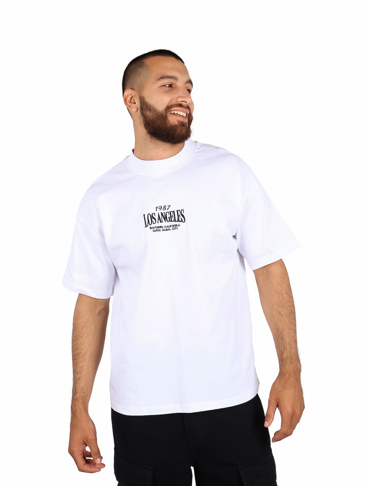 Hombre vistiendo playera blanca de manga corta con estampado de Los Angeles en el pecho.