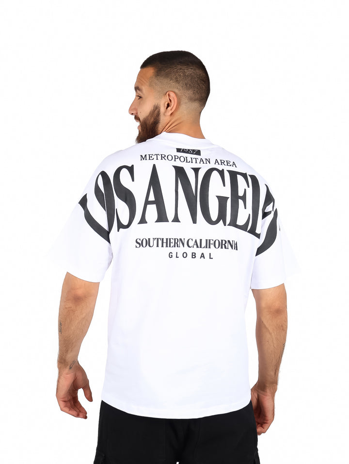 Hombre vistiendo playera blanca de manga corta con estampado de Los Angeles en el pecho.