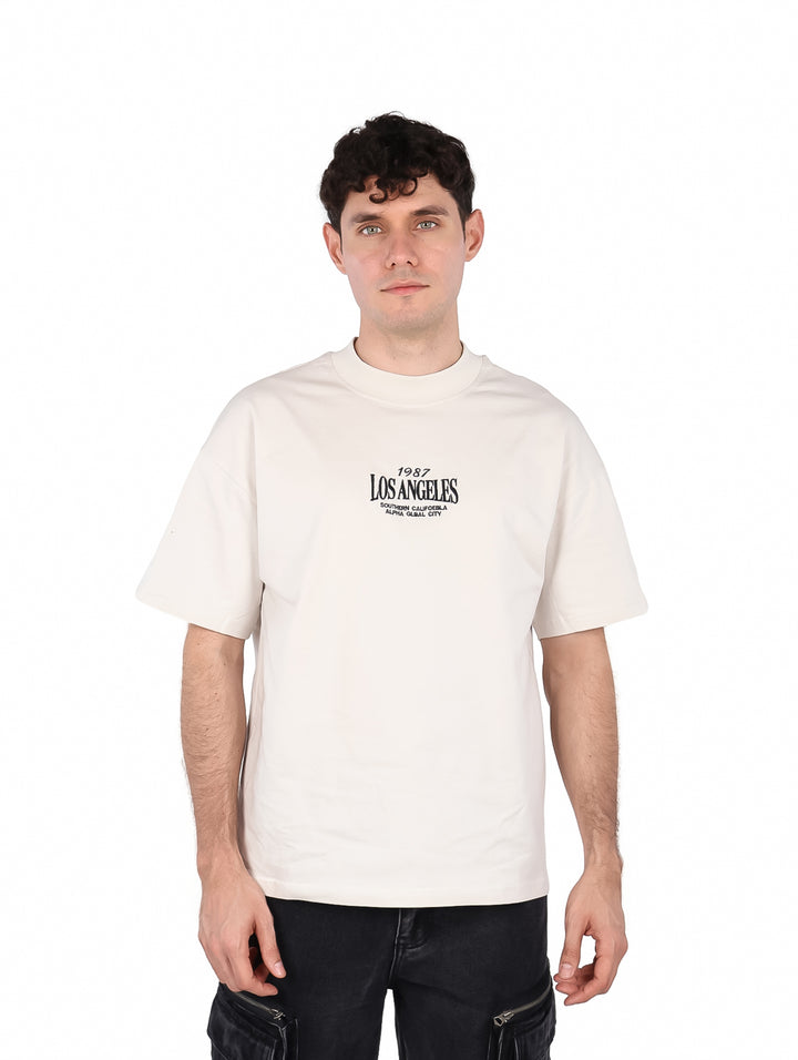 Hombre vistiendo una playera color beige con texto de Los Angeles en el pecho.
