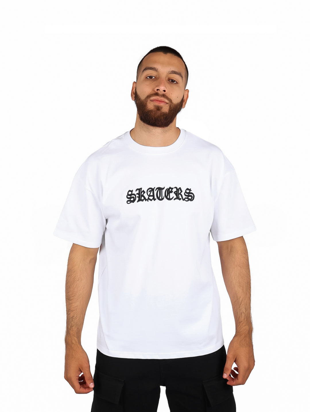 Hombre vistiendo playera blanca de manga corta con el texto SKATERS en letras negras.
