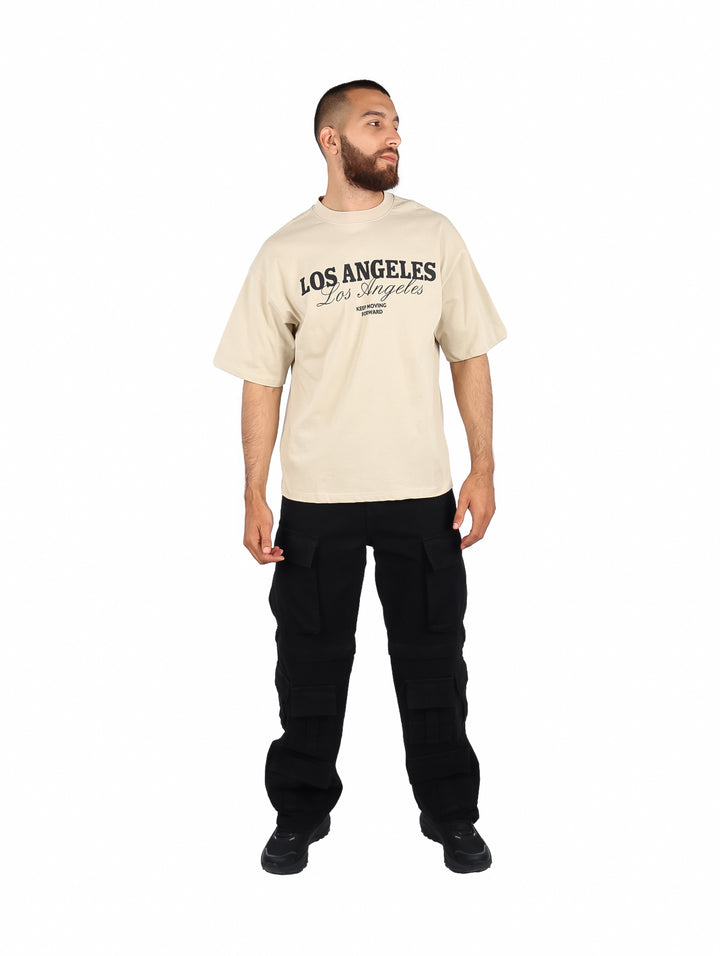 Hombre vistiendo playera color kaki de manga corta con estampado de Los Angeles en el pecho.