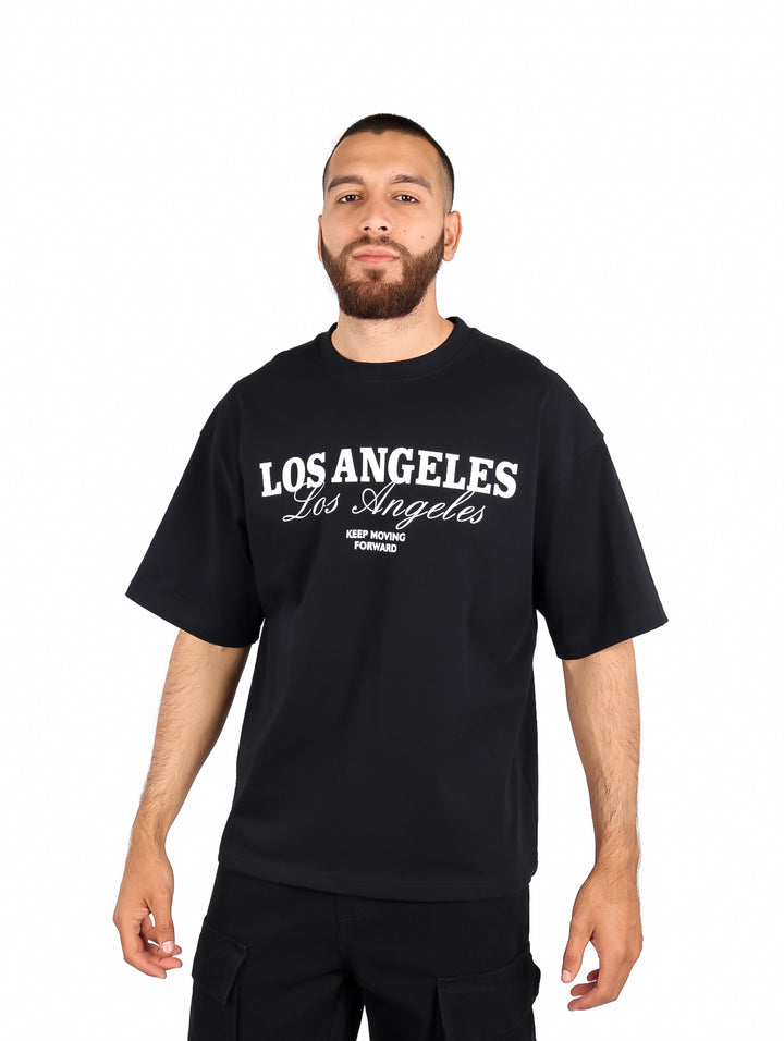 Hombre vistiendo playera color negro de manga corta con estampado blanco de Los Angeles.