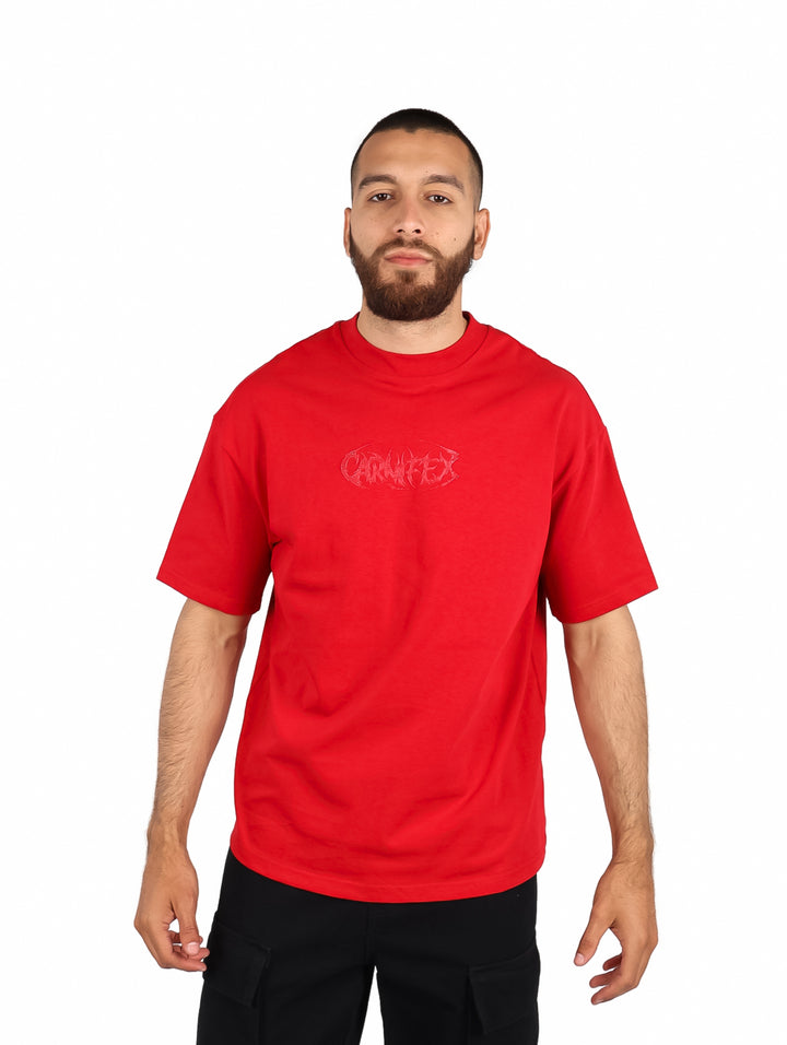 Hombre vistiendo una playera roja de manga corta con un diseño gráfico en el pecho.