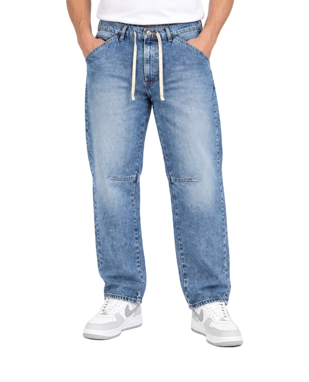 Hombre vistiendo pantalones tipo jogger de mezclilla azul claro con cordones blancos en la cintura.