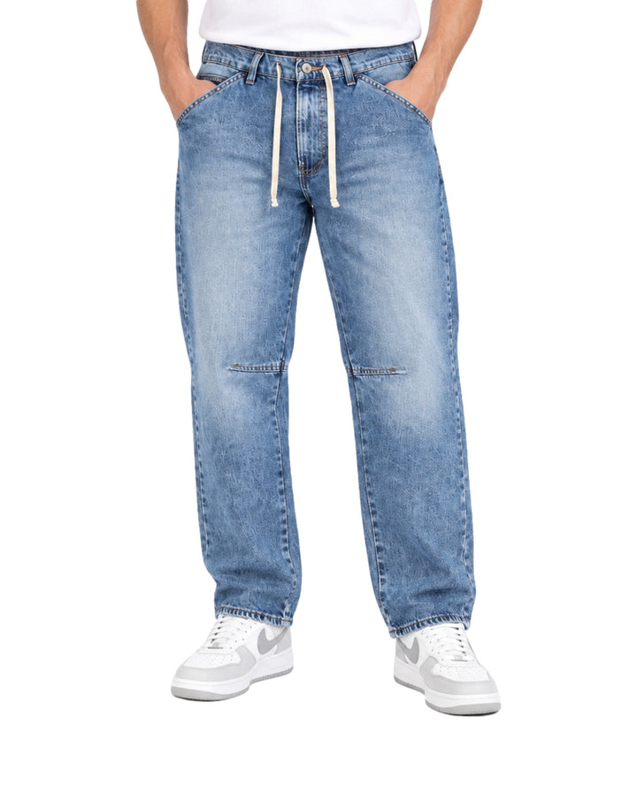 Hombre vistiendo pantalones tipo jogger de mezclilla azul claro con cordones blancos en la cintura.