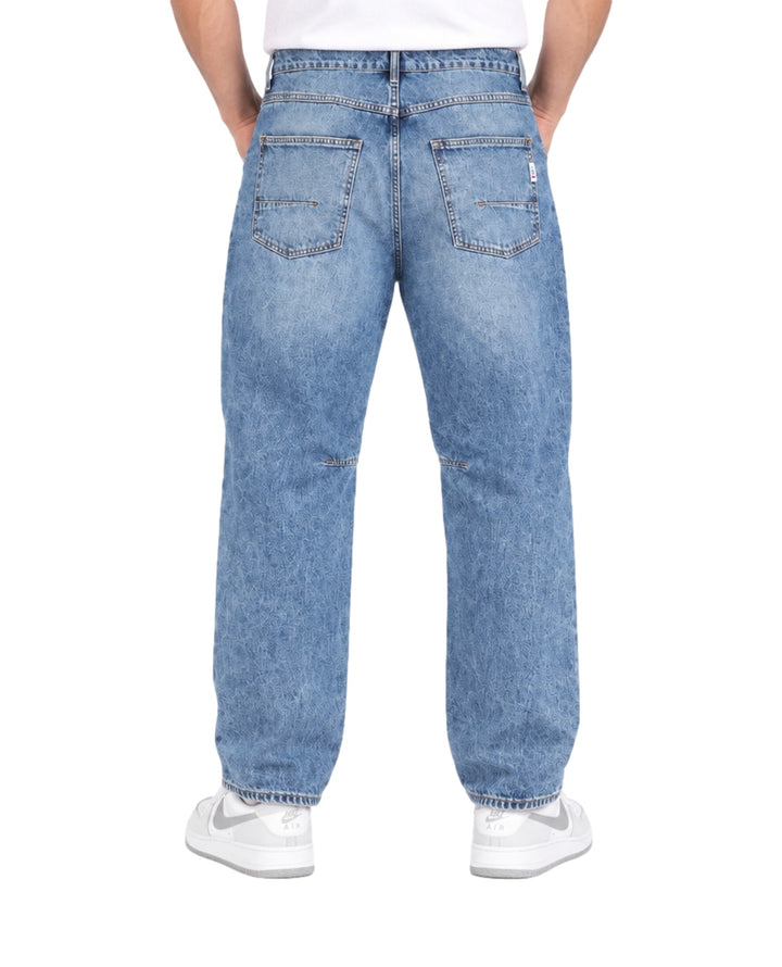 Hombre vistiendo pantalones tipo jogger de mezclilla azul claro con cordones blancos en la cintura.