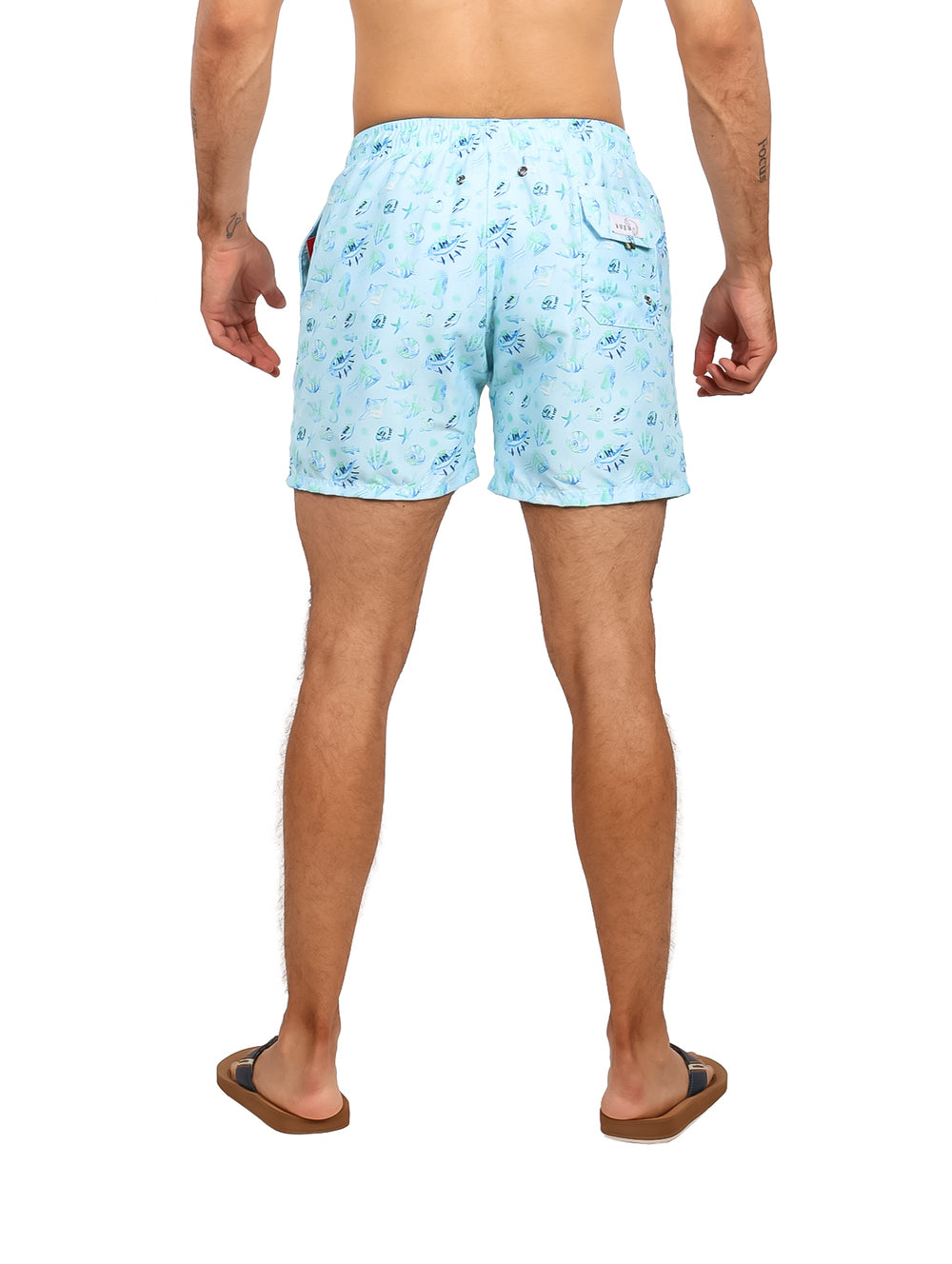 Hombre vistiendo traje de baño corto color aqua con estampado blanco y cordón ajustable en la cintura.