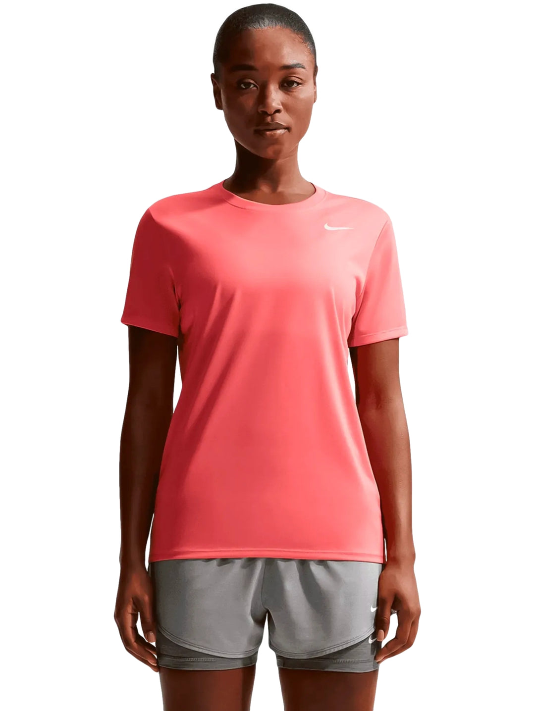 Mujer vistiendo playera deportiva Nike color coral y pantalones cortos grises.
