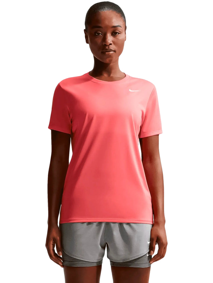 Mujer vistiendo playera deportiva Nike color coral y pantalones cortos grises.