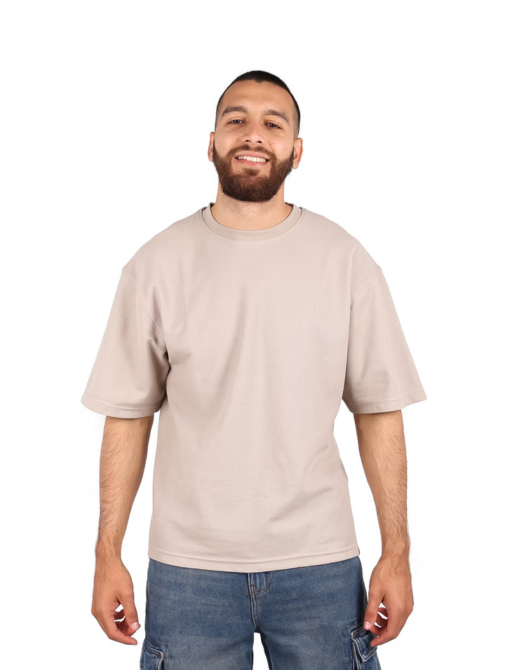 Hombre vistiendo una playera color beige de manga corta y cuello redondo.