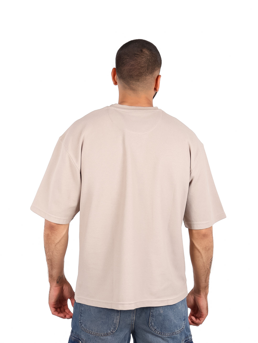 Hombre vistiendo una playera color beige de manga corta y cuello redondo.