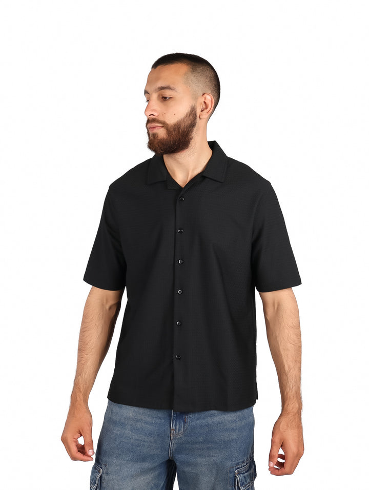 Hombre vistiendo una camisa negra de manga corta con botones y cuello.