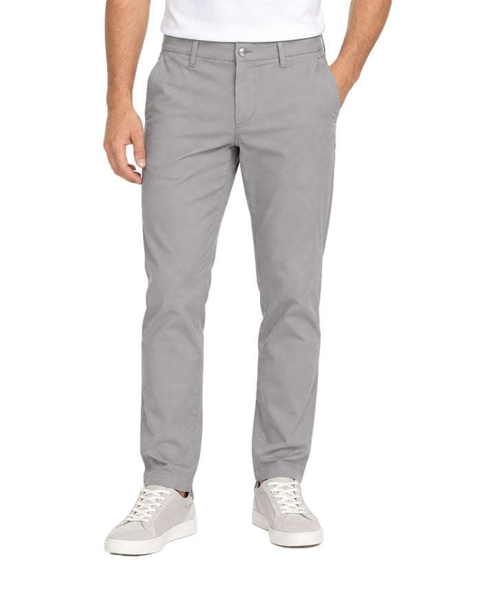 Hombre vistiendo un pantalón casual color gris de corte recto con tenis blancos.