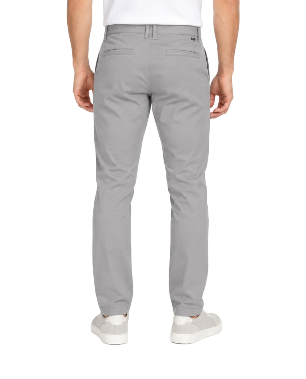 Hombre vistiendo un pantalón casual color gris de corte recto con tenis blancos.