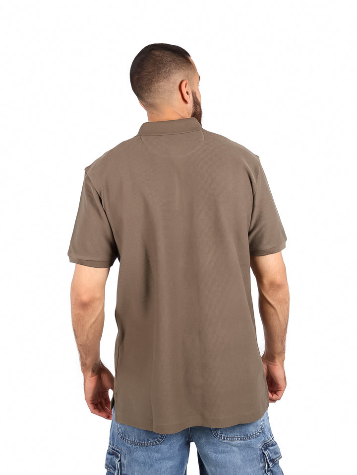Hombre vistiendo una playera polo color olivo de manga corta.