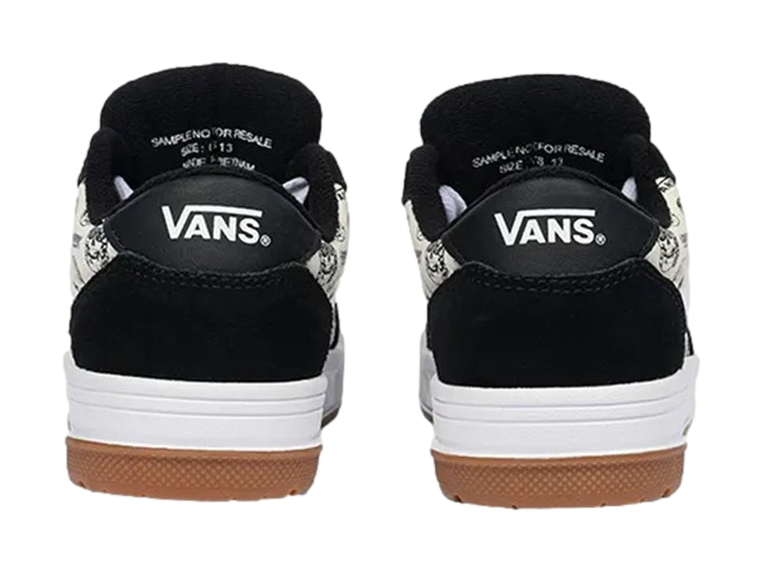Tenis Vans blancos y negros con estampado de calaveras y suela de goma color marrón.