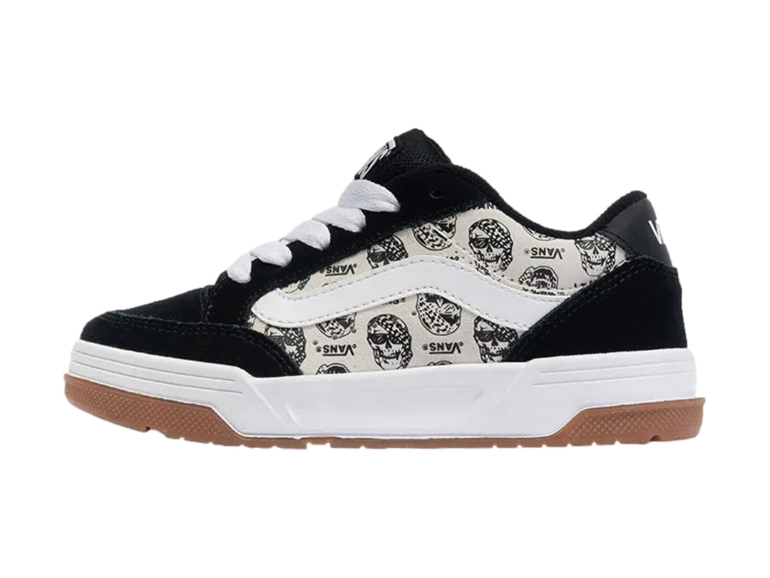 Tenis Vans blancos y negros con estampado de calaveras y suela de goma color marrón.