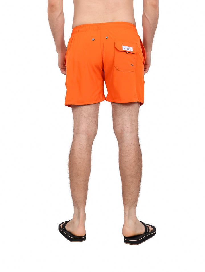 Hombre vistiendo traje de baño corto color naranja con cordón blanco.