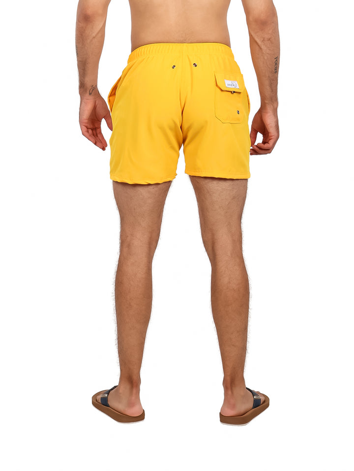 Hombre vistiendo un traje de baño corto de color amarillo con cordón blanco.